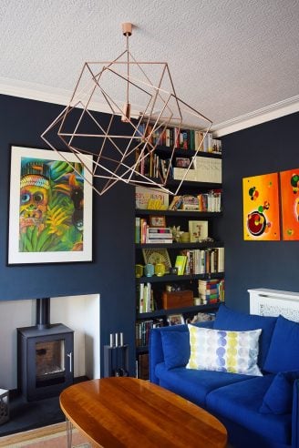 Cosy Lounge With Dark Walls, Wood Burner, Floating Shelves and Colourful Art | Little House On The Corner