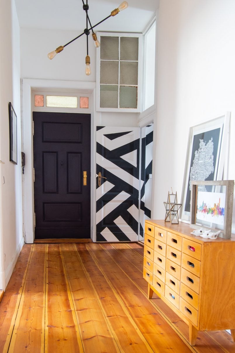 Hallway with sanded floorboards and paean black front door | Little House On The Corner